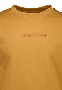 Senapsgul crewneck sweatshirt i mjukt material, med präglad "LINDBERGH" branding framtill. Slät textur, enkel design.