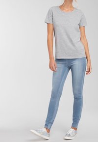 Szara bawełniana koszulka z okrągłym dekoltem, zestawiona z jasnoniebieskimi rurkami i iryzującymi trampkami. Casualowy fason, dopasowana sylwetka.