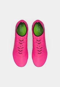 Růžové sportovní boty s elegantním designem, černými detaily, texturovaným svrškem a zelenou vzorovanou vložkou.