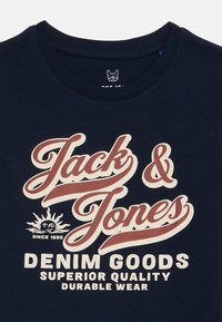 Marineblaue Baumwoll-T-Shirt mit auffälligem, cremefarbenem und kastanienbraunem Text: "Jack & Jones Denim Goods Superior Quality Durable Wear."