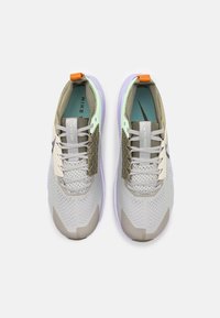 Baskets de sport grises avec des accents vert olive, présentant un dessus texturé, un design à lacets, une semelle extérieure lavande et un logo sur la languette.