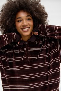 Pullover a righe color mogano con collo a zip, caratterizzato da sottili strisce bianche e rosa chiaro a contrasto. Texture morbida con una vestibilità comoda.