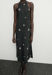 Robe noire en lin à col licou ornée d'une broderie circulaire argentée, de coupe droite, avec des fentes latérales et une texture lisse.