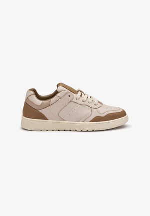 Lage casual sneaker met bovenwerk van beige suède, bruine leren accenten, witte veters en een dikke witte rubberen zool, gezien vanaf de zijkant.