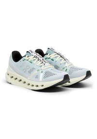 Hellblaue Laufschuhe mit einem Obermaterial aus Mesh, strukturierten Akzenten, weißen Schnürsenkeln und einer gepolsterten Sohle mit auffälligen rundlichen Ausschnitten.
