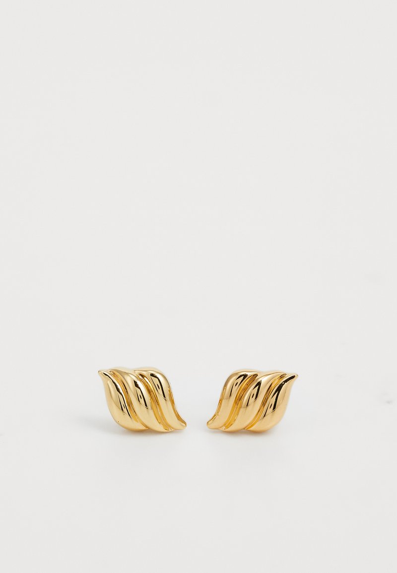 Pendientes de metal en tono dorado que presentan un diseño en forma de ola con tres curvas fluidas, reflejando la luz con una textura brillante y suave.