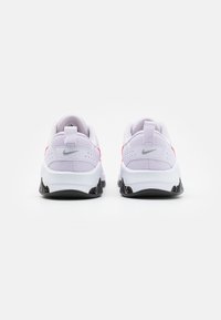 Bílé sportovní tenisky s měkkým síťovaným svrškem a růžovými akcenty. Mají polstrovaný límec, černou gumovou podrážku a logo na boku.