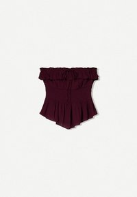 Top bordeaux senza spalle con dettagli a volant, corpino arricciato e orlo svasato. Realizzato in tessuto leggero con una texture morbida.