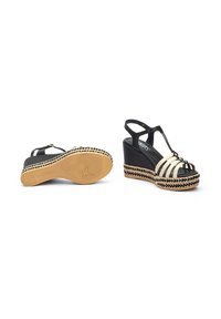 Sandalias de cuña en blanco y negro con un upper de tela texturizada, que presentan una suela de yute trenzado y un diseño de tira en T con una correa en el tobillo ajustable.
