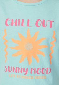 Hellblaue Baumwoll-T-Shirt mit einem grafischen Design, das eine gelbe Sonne und pinken Text zeigt: "CHILL OUT SUNNY MOOD LET SUMMER BEGIN."