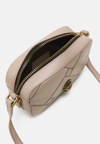 Růžová kožená crossbody taška s prošívaným vzorem, zlatým zipem a detaily kovových prvků. Interiér má tmavé podšívání a značkovou nálepku.
