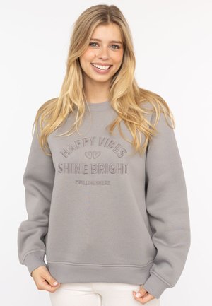 Grauer Sweatshirt mit gerippten Bündchen und Saum, ausgestattet mit geprägt Text "HAPPY VIBES SHINE BRIGHT" in einem lässigen, lockeren Schnitt.