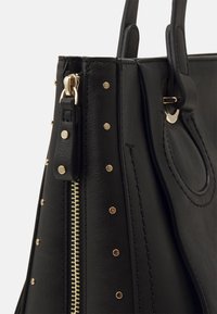 Bolso de mano de cuero negro con herrajes dorados, con cierre de cremallera, acentos de tachuelas y acabado texturizado en el cuerpo principal.