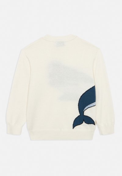 Pull crème avec un grand motif de queue de baleine bleu marine sur le bas du dos, côté droit.