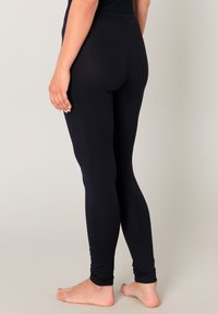 Zwarte legging gemaakt van rekbare stof, die strak aansluit van taille tot enkel met een effen textuur en een gladde afwerking.