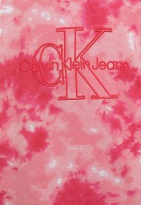 T-shirt tie-dye rosa con la scritta "Calvin Klein Jeans" ricamata in corallo-rosso. Tessuto di cotone morbido con finitura testurizzata e variazione vivace di colore.
