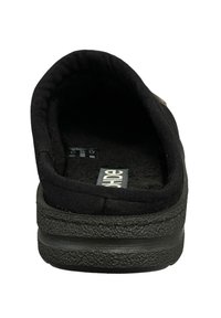 Chaussure noire à enfiler avec un upper en tissu doux, une doublure moelleuse et une semelle en caoutchouc texturé. Design minimaliste sans matériel visible ni motifs.