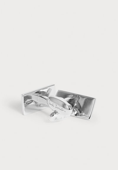 Paire de boutons de manchette rectangulaires en argent brillant avec des fermoirs ovales gravés d'un nom de marque sur fond blanc.