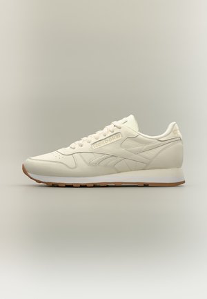 Baskets Reebok couleur crème avec tige en cuir, design à lacets et semelle en gomme sur un fond neutre uni.