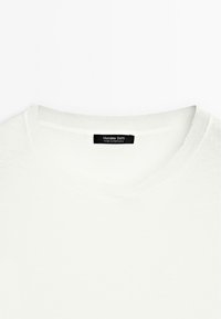 T-shirt bianca in cotone con scollo rotondo, texture liscia e un piccolo etichetta nera con "Massimo Dutti" all'interno del colletto.