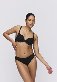 Black lace lingerie set featuring a padded bra with adjustable straps and matching bikini. Smooth fabric with scalloped lace edges.