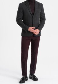 Szary, kratkowany, dopasowany blezer z klapami z wycięciem, zestawiony z bordowymi, wąskimi spodniami i czarnymi skórzanymi butami. Gładka faktura, wyraźnie zarysowana konstrukcja.