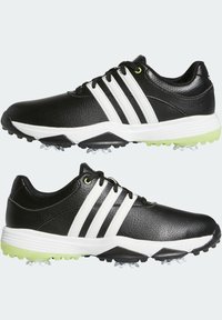 Czarne buty golfowe z białymi paskami, skórzana cholewka o fakturowanej powierzchni, wyściełana podeszwa oraz zielony akcent na podeszwie zewnętrznej. Zawierają formowane kolce dla lepszej przyczepności.