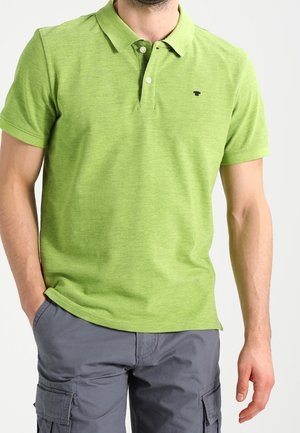 Polo vert avec une finition texturée, doté d'une patte de boutonnage à trois boutons et d'un petit logo sur la poitrine. Associé à un short cargo gris.