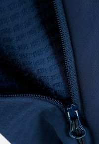 Tejido de mezcla de navy con cremallera que muestra una textura suave y un patrón interior a rayas. Detalle de cremallera metálica visible y costura.