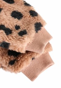 Tessuto marrone fuzzy con macchie nere, caratterizzato da polsini a coste color beige. La texture appare morbida e pelosa, progettata per offrire comfort e calore.