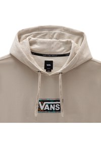 Beige hoodie met een trekkoordkap, textuurstof en een voorkleurpatch met het Vans-logo tegen een patroonachtergrond.