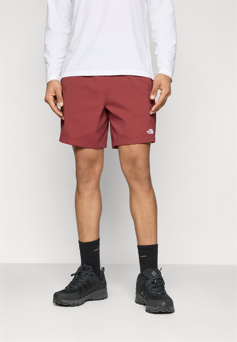 Bordo kupaće hlačice s elastičnom vezicom i logotipom The North Face. Uparen s crnim planinarskim cipelama i tamnim čarapama. Bijela majica dugih rukava.