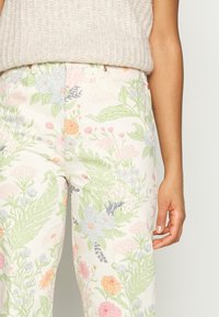Pantalones con estampado floral en tela ligera; presenta tonos pastel de rosa, azul y verde; incluye hojas verdes y diversos diseños de flores.