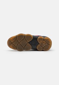 Semelle de sneaker FILA en caoutchouc noir avec un design texturé ; présente des motifs circulaires et hexagonaux ; accents en caoutchouc transparent.
