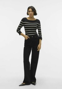 Mustvalged triibuline, soonikuga pikkade varrukatega pluus, millele on lisatud kõrge vöökohaga mustad teksad ja terava ninaga mustad madalad kingad.