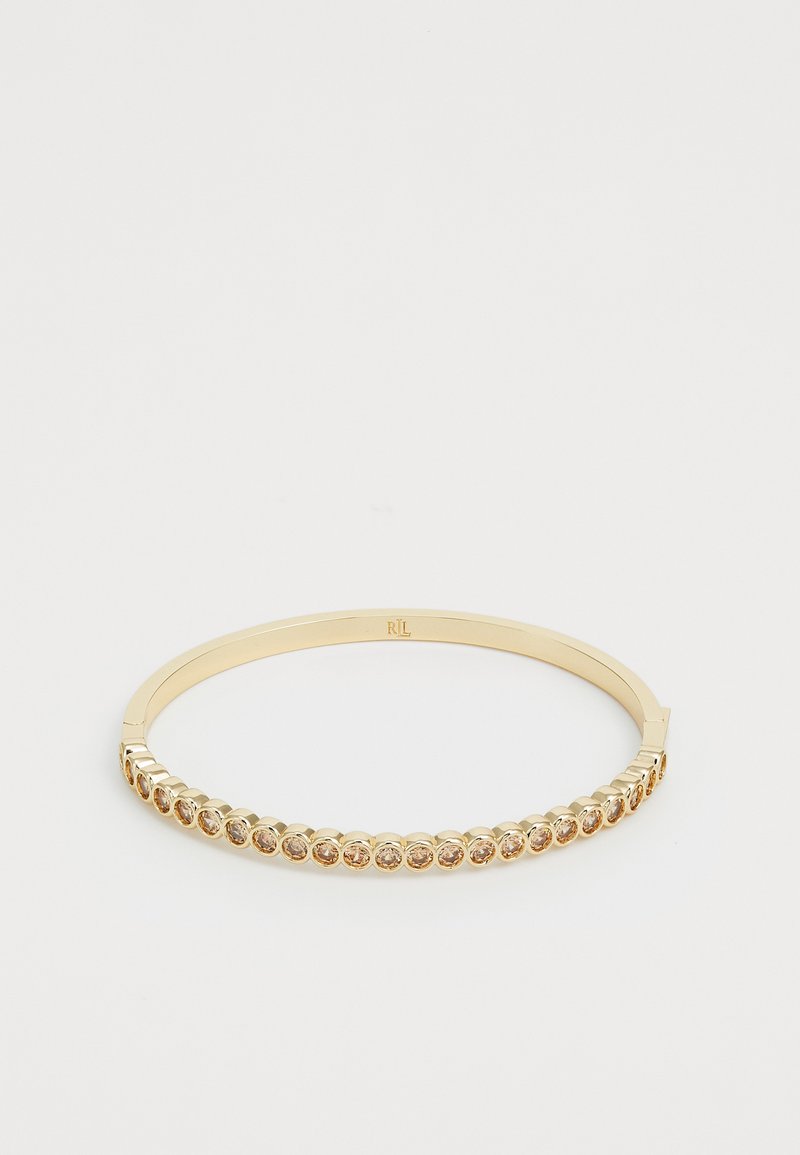 Bracciale rigido in oro con una fila di pietre scintillanti racchiuse in impostazioni circolari, esterno lisciato e una discreta incisione del marchio.