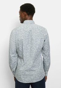 Langarmhemd mit hellem Hintergrund und floralem Muster in Blau- und Grüntönen, ausgestattet mit klassischem Kragen und Knopfmanschetten.