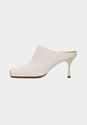 Mule couleur crème avec bout pointu et talon stiletto mince de hauteur moyenne, vue de profil sur un fond clair uni.