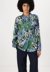 Bluza z dolgimi rokavi iz lahkega materiala, ki se ponaša s pisano modro, zeleno in črno cvetličnim ter ptičjim potiskom, z ovratnikom na gumb in sproščenim krojem.