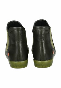 Botas de tobillo de cuero negro con lados de textil verde. Punta redonda, superficie texturizada y un acento rojo cerca del tacón. Suela plana de goma.