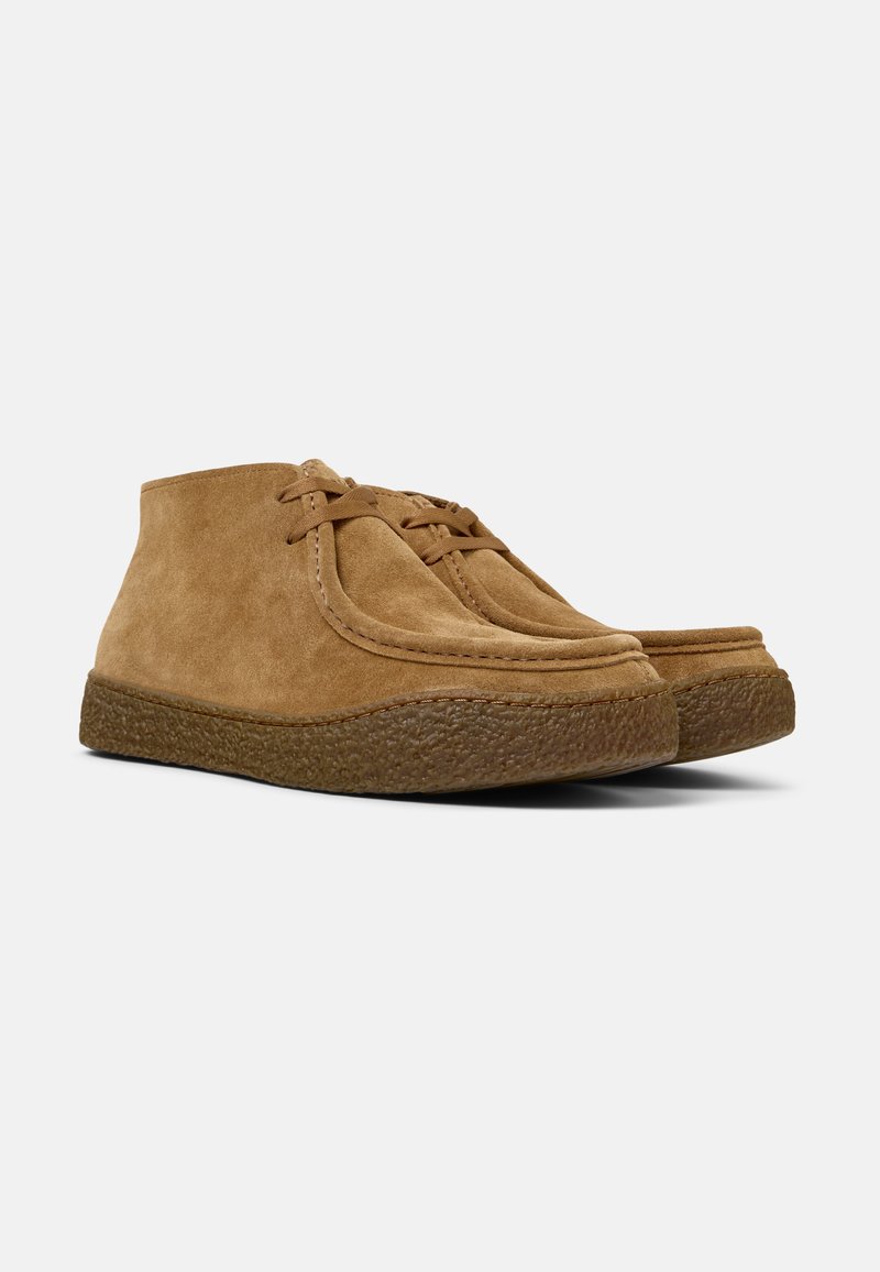 Tan suede ankle boots with rounded toe, rubber sole, and lace-up design. Notable textured detailing along the sole edge.