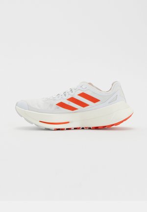 Bielo-oranžový bežecký topánka Adidas s tromi oranžovými pruhmi na strane a hrubou polstrovanou podrážkou.
