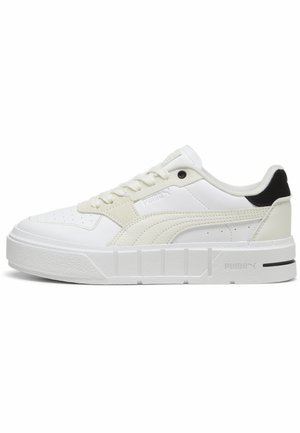 Zapatillas blancas con un diseño texturizado, con parte superior de cuero suave, caja de dedos perforada, talón negro en contraste y suela blanca gruesa.