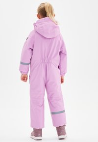 Roze winteroverall met een capuchon, elastische taille en reflecterende accenten. Gelaagde pasvorm met lange mouwen en omgeslagen enkels.