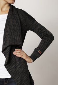 Lång mörkgrå cardigan med ribbat mönster, öppen framtid och draperad krage. Har en brun detalj vid ärmslutet och en avslappnad passform.