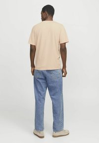 Beige korte mouw t-shirt met een klassieke ronde hals, gecombineerd met een relaxte pasvorm blauwe denim jeans. Zachte stof, casual ontwerp.