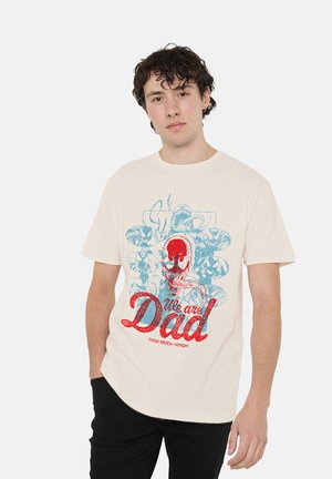 Young man with curly dark hair wearing a white t-shirt with red and blue Venom-themed graphic and text "We are Dad."