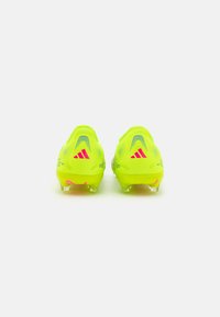 Des crampons de football en néon jaune vif avec des accents roses. Présentant une surface texturée, un design à l'arrière et des crampons en plastique transparent pour la traction.