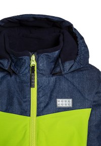 Giubbotto con cappuccio per bambino, con sezione superiore blu scuro, sezione inferiore giallo-verde brillante, cerniera giallo-verde e patch con logo LEGO sul petto.