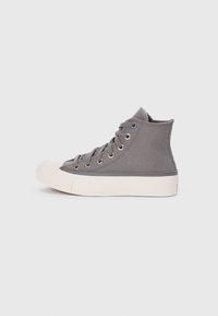 High-top gray canvas sneaker with rubber sole, metal eyelets, and flat laces. Features a white toe cap and midsole detailing.